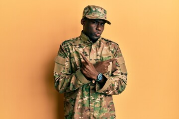 Young african american man wearing army uniform pointing to both sides with fingers, different...