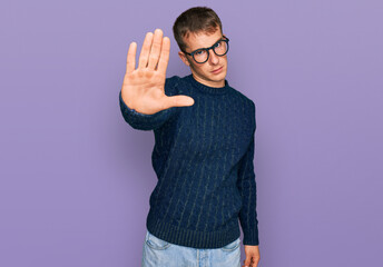 Young blond man wearing casual clothes and glasses doing stop sing with palm of the hand. warning expression with negative and serious gesture on the face.