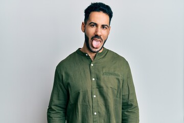 Young hispanic man wearing casual clothes sticking tongue out happy with funny expression. emotion concept.