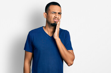 Young african american man wearing casual t shirt touching mouth with hand with painful expression because of toothache or dental illness on teeth. dentist