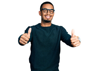 Young african american man wearing casual clothes and glasses approving doing positive gesture with hand, thumbs up smiling and happy for success. winner gesture.