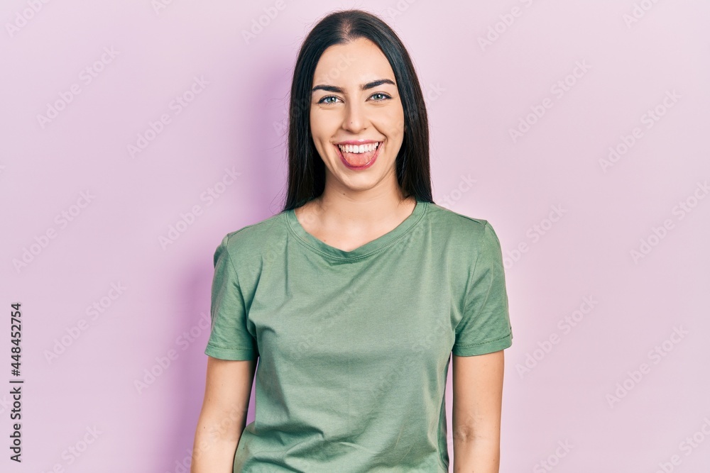 Poster beautiful woman with blue eyes wearing casual t shirt sticking tongue out happy with funny expressio