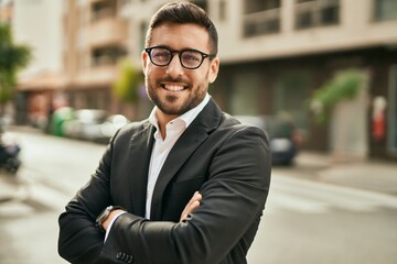 Young hispanic businessman with arms crossed smiling happy at the city.