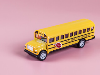 School bus isolated on pink.
An isolated toy school bus stands on the right on a pink background...