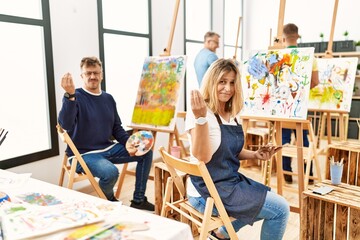 Group of middle age artist at art studio doing italian gesture with hand and fingers confident expression
