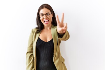 Young brunette woman standing over isolated background showing and pointing up with fingers number two while smiling confident and happy.