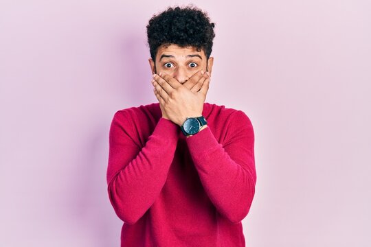 Young arab man with beard wearing casual pink sweater shocked covering mouth with hands for mistake. secret concept.