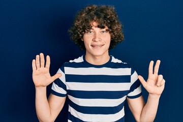 Fototapeta premium Handsome young man wearing casual striped t shirt showing and pointing up with fingers number eight while smiling confident and happy.