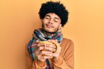 Hispanic man with afro hair smelling coffee aroma relaxed with eyes closed