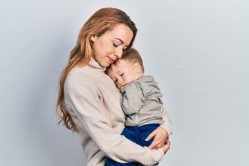 Young caucasian woman holding and hugging her son with love. Family of two bonding together. Mother holding infant toddler