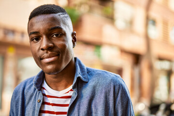 Young african american man with relaxed expression standing at the city.