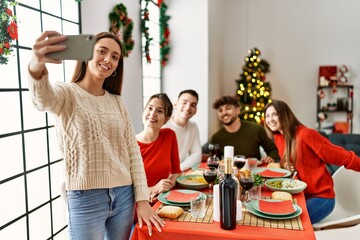 Group of young people having christmas dinner make selfie by the smartphone at home.
