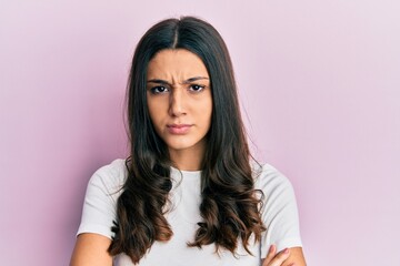 Fototapeta premium Young hispanic woman wearing casual white t shirt skeptic and nervous, disapproving expression on face with crossed arms. negative person.