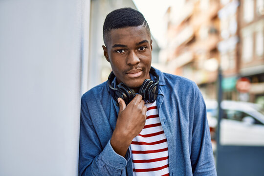 Young african american man with serious expression using headphones at the city.