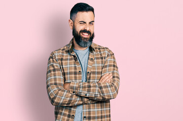 Hispanic man with beard with arms crossed gesture winking looking at the camera with sexy...