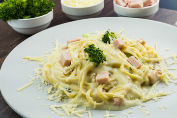 Delicious Fettuccine with white sauce, broccoli, turkey breast cubes and grated cheese. Selective focus.