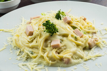 Delicious Fettuccine with white sauce, broccoli, turkey breast cubes and grated cheese. Selective focus.