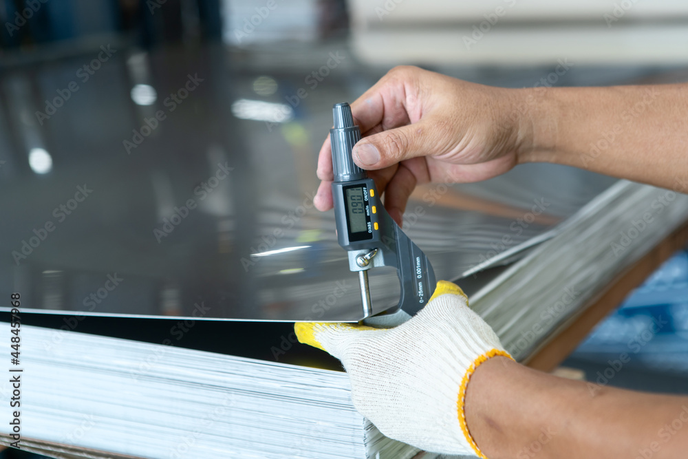 Wall mural the photo shows how to measure how thick of the metal sheet by using digital thickness gauge.