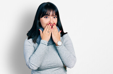 Young hispanic plus size woman wearing winter scarf laughing and embarrassed giggle covering mouth with hands, gossip and scandal concept