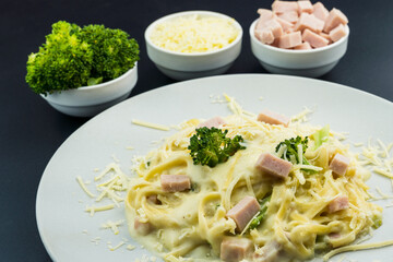 Delicious Fettuccine with white sauce, broccoli, turkey breast cubes and grated cheese. Selective focus.