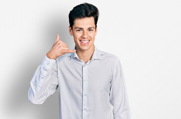 Young hispanic business man wearing business clothes smiling doing phone gesture with hand and fingers like talking on the telephone. communicating concepts.