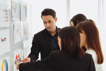 Businessman or manager presents a discussion graph, a strategic planning report, and discusses ways to increase profits with colleagues at the workshop. Brainstorming and teamwork concept.