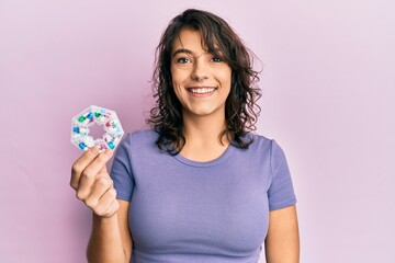 Young hispanic woman holding pill organizer looking positive and happy standing and smiling with a confident smile showing teeth