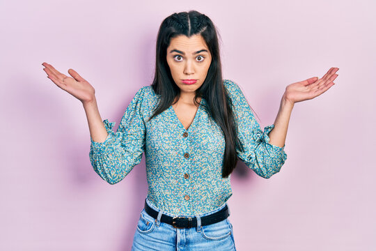 Young hispanic girl wearing casual clothes clueless and confused with open arms, no idea and doubtful face.
