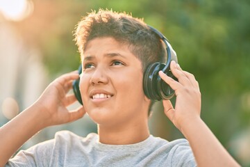 Adorable latin boy smiling happy using headphones at the city.