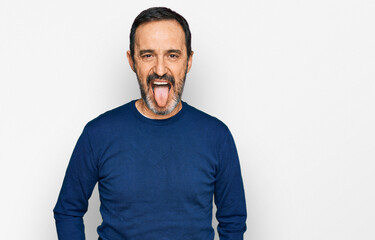 Middle age hispanic man wearing casual clothes sticking tongue out happy with funny expression. emotion concept.