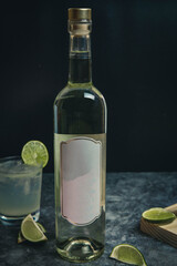 Bottle of vodka, white wine, pisco on black background. Drink with lime on black marble. White label without mark.