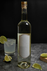 Bottle of vodka, white wine, pisco on black background. Drink with lime on black marble. White label without mark.