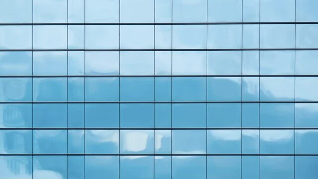 Time lapse of blue sky and clouds reflected in structural modular glass wall.