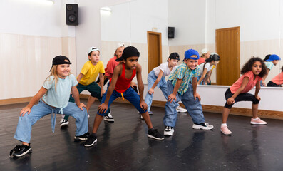 Smiling girls and boys hip hop dancers doing dance workout during group class