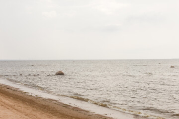 Fototapeta na wymiar Cloudy day at Baltic sea coast near Saint Petersburg, Russia. Sandy shore. Rocks in water