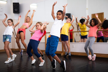 Group of children participating in dance class, following their teacher in dance school..