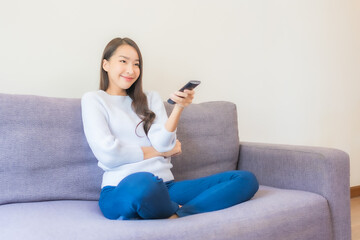 Obraz premium Portrait beautiful young asian woman use remote for change channel