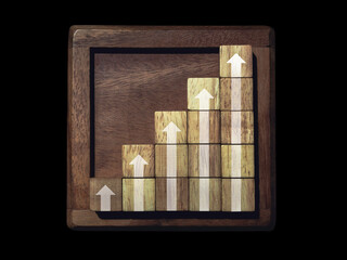 Rising up arrows on wooden blocks chart steps with on wooden frame isolated on black background, business growth process, and economic improvement concept.