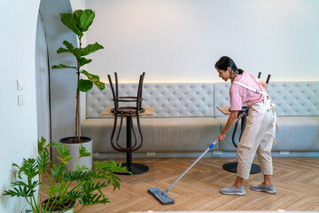 Young Asian woman coffee shop barista cleaning cafe before opening. Female waitress preparing...