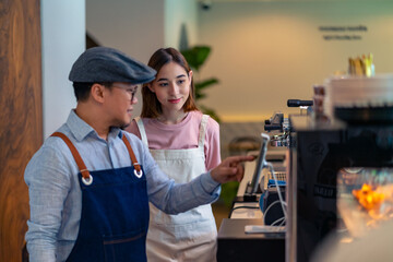 Asian male coffee shop manager teaching young woman staff working on digital tablet. Small business cafe and restaurant owner instruct part time employee preparing service to customers before opening
