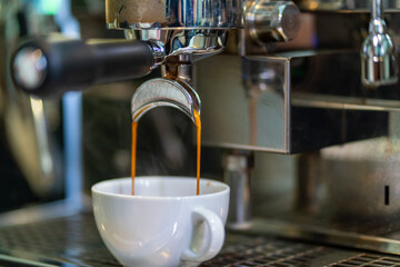 Close up of coffee machine pouring hot espresso in coffee cup for making latte. Barista brewing black coffee at coffee shop in the morning. Small business cafe restaurant food and drink concept