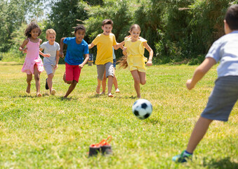Cheerful children are jogning with ball on the playground