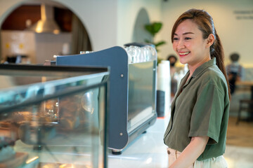 Asian woman coffee shop employee barista working at cafe. Smiling female waitress cashier taking...