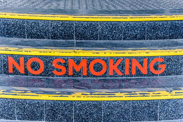 A No Smoking sign in red lettering on a curved tile staircase