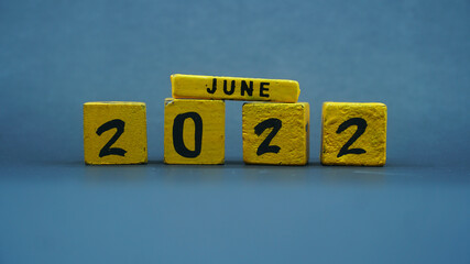 Wooden block calendar for June 2022. Yellow on a dark background
