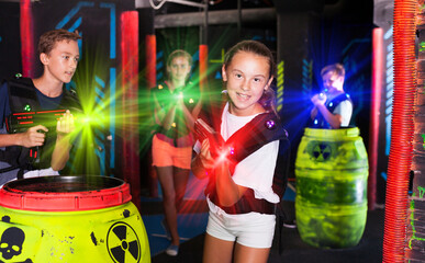 Portrait of teenager girl with laser gun having fun on dark lasertag arena..