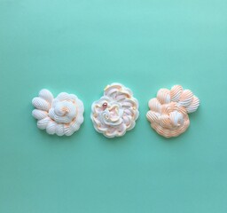 Three meringue seashells on a green background