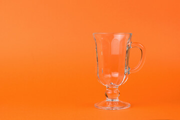 An empty glass coffee glass on an orange background.