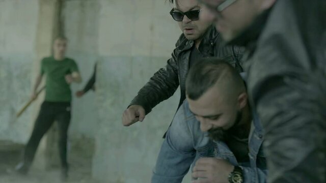 4k Group of men fighting in abandoned building . Friends helping each other during the fight . Drug deal between criminal gangs goes wrong & a fight breaks out .  Staged, scenic shot with artists