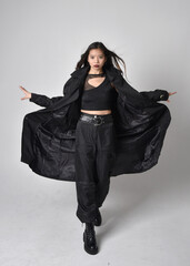 Full length portrait of pretty young asian girl wearing black tank top, utilitarian  pants, leather...